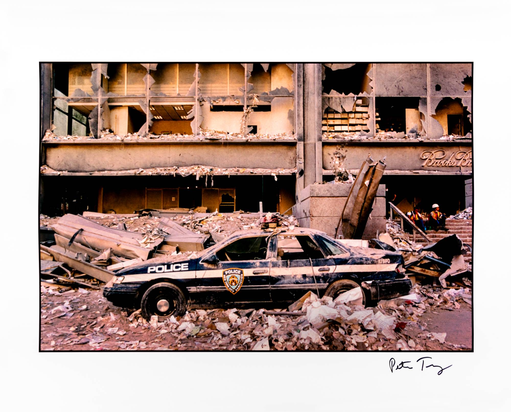 police car covered in rubble in front of a destroyed office building in New York City the day after 9/11